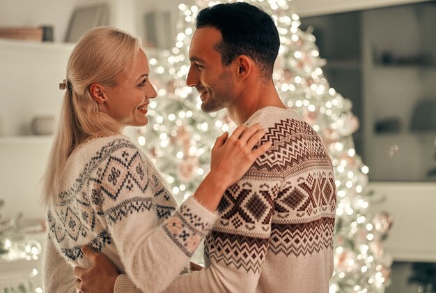 Der Mann und die Frau, die auf dem Weihnachtsbaumhintergrund stehen