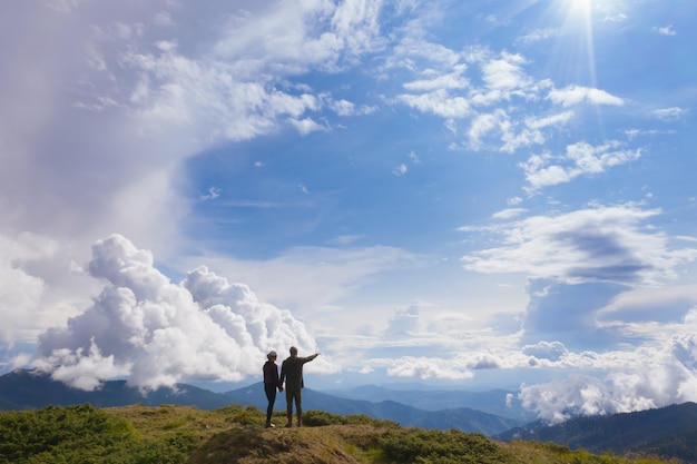 Der Mann und die Frau, die auf einem Berg gegen schöne Wolken stehen