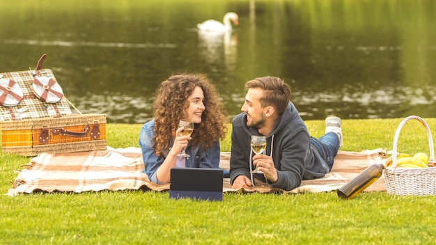 Der Mann und die Frau mit einer Tablette legen sich hin und trinken einen Wein