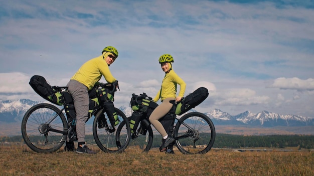 Der Mann und die Frau reisen auf Fahrradtouren in gemischtem Gelände mit Bikepacking. Das Liebespaar reist mit Zelt und Fahrradtaschen an. Stylische Sportbekleidung.