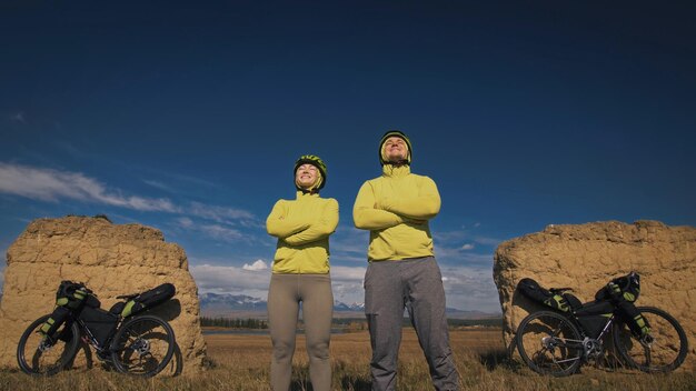 Der Mann und die Frau reisen auf Fahrradtouren in gemischtem Gelände mit Bikepacking. Die beiden Personen reisen mit Fahrradtaschen an. Berg schneebedeckt, Steinbogen.