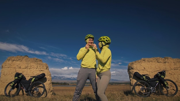 Der Mann und die Frau reisen auf gemischtem Gelände Fahrradtouren mit Bikepacking Die zwei Personen reisen mit Fahrradtaschen Sportsportbekleidung in grün-schwarzen Farben Berg schneebedeckter Steinbogen