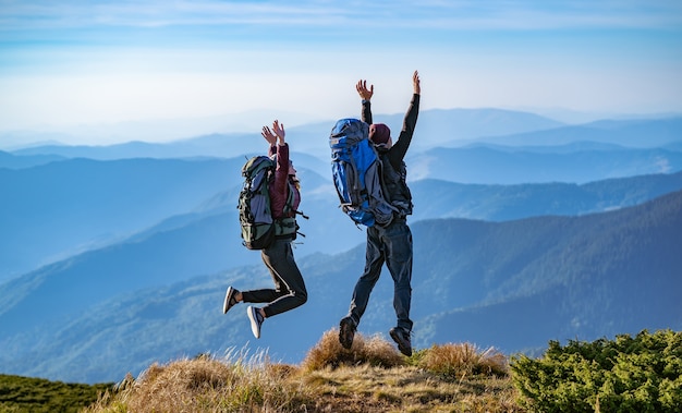 Der Mann und eine Frau mit Rucksäcken springen auf den Berg