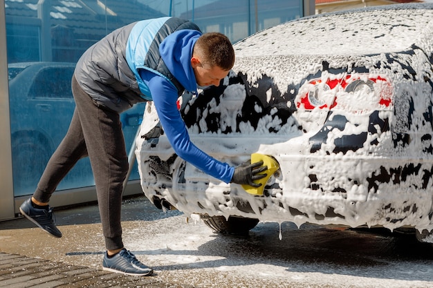 Der Mann wäscht sein Auto auf Selbstbedienungsautowaschanlage. Express Autowaschanlage