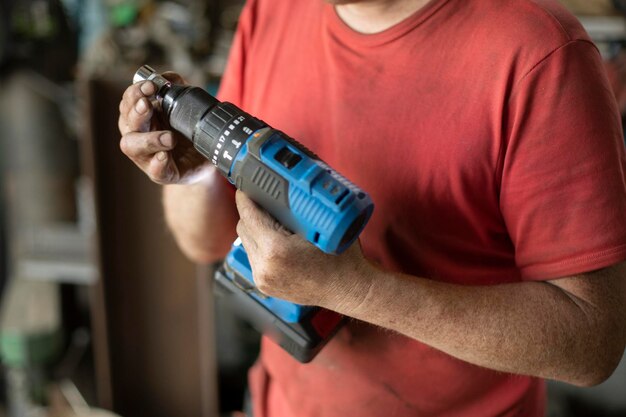 Foto der mann zeigt einem schraubendreher einen kerl in einer werkstatt mit einem elektrowerkzeug in der hand