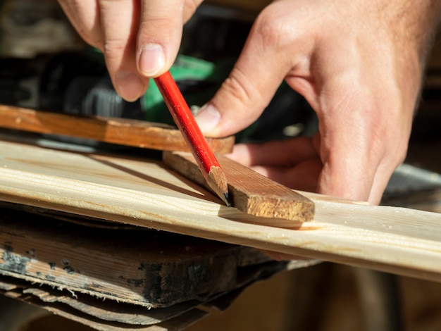 Der Mann zieht mit einem Bleistift eine Linie auf die Bauplatte und misst den gewünschten Winkel