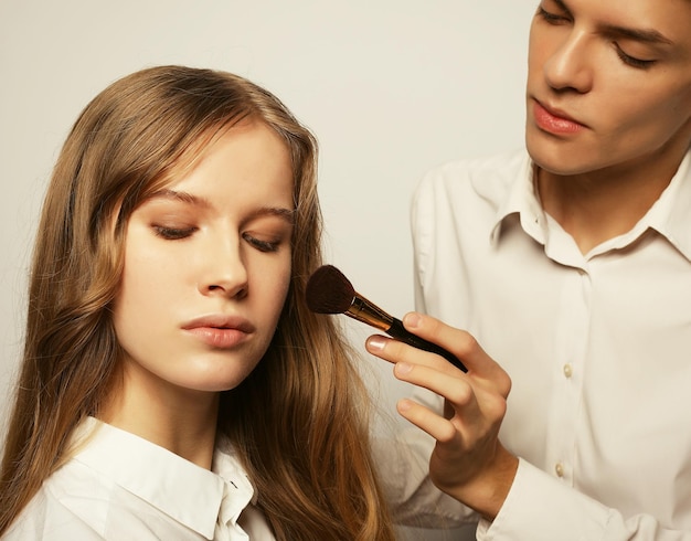 Der Maskenbildner, der Fachmann tut, bilden von der jungen Frau