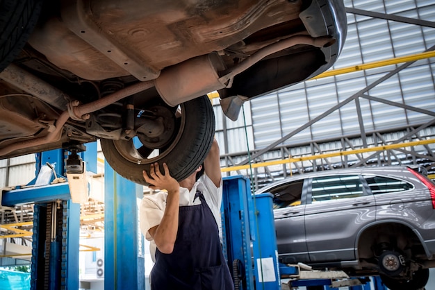 Der mechaniker, der auto ändert, drehen herein autowerkstatt