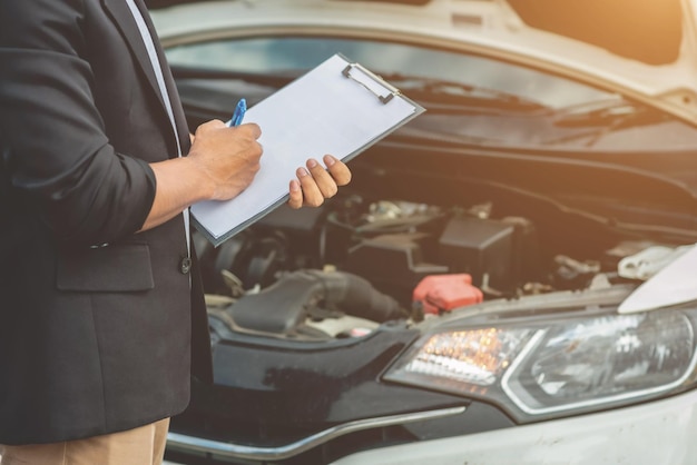 Der Mechaniker, der das Auto wartet, zeichnet die Ergebnisse der Autoinspektion auf