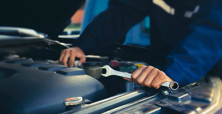 Der Mechaniker repariert den Motor des Autos in der Autoreparatur