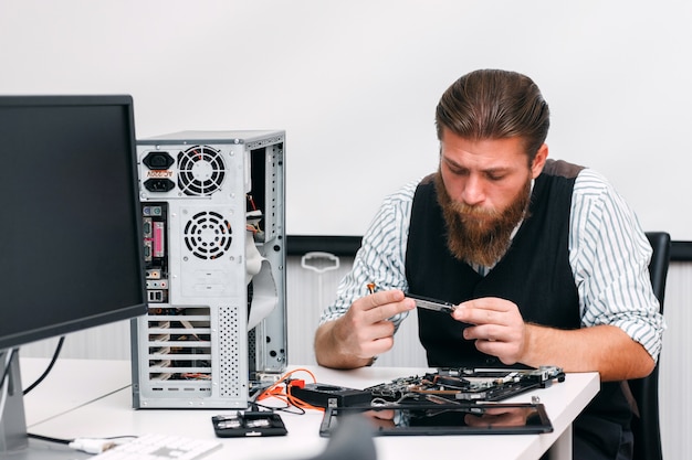 Der Mechaniker untersucht den inneren Teil des Computers. Ingenieur, der Schaltung der zerlegten CPU in der Reparaturwerkstatt betrachtet. Elektronische Renovierung, Reparatur, Entwicklungskonzept