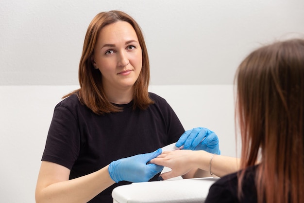 Der Meister im Schönheitssalon macht dem Mädchen eine Maniküre