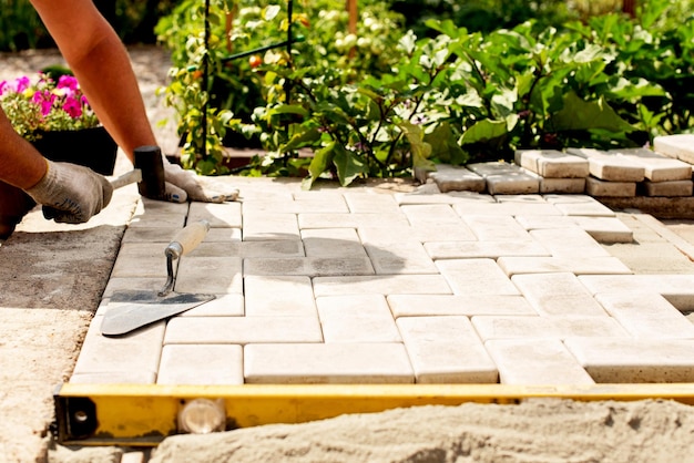 Der Meister legt Pflastersteine in Schichten Garten Ziegelstein Pflasterweg durch professionellen Pflasterarbeiter