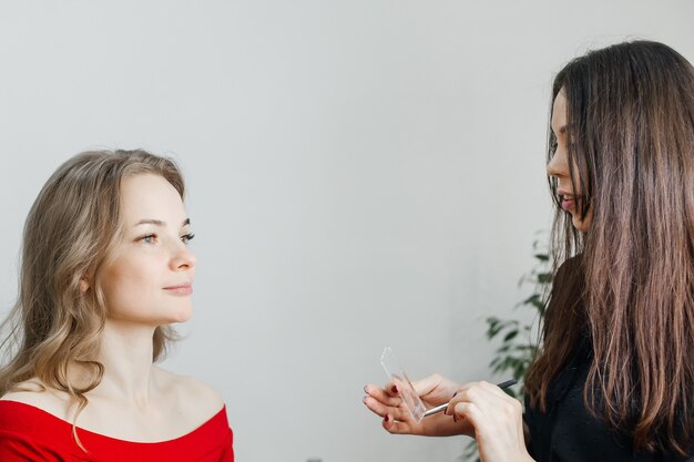 Der Meister macht ein schönes blondes Make-up in einem Schönheitssalon