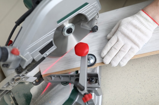 Der Meister schneidet die Laminatplatte auf der Schreibmaschine