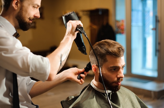 Der Meister schneidet im Friseursalon Haare und Bart von Männern