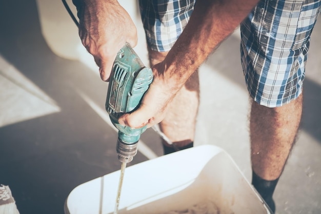 Der Mensch arbeitet mit einem Bohrer