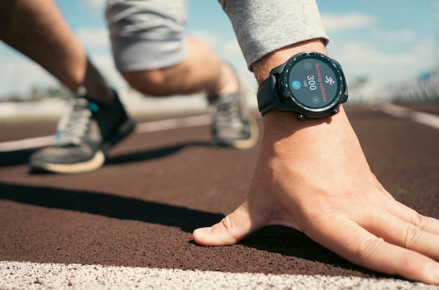 Der Mensch bereitet sich darauf vor, auf einer Laufband-Smartwatch auf der Hand des Athleten zu starten Anwendungen für Smartwatch für das Outdoor-Training