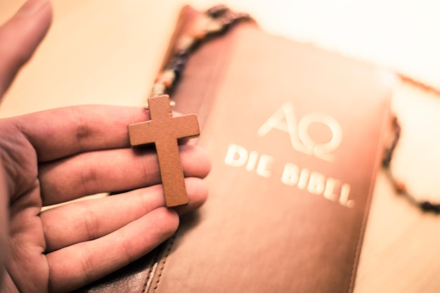 Der Mensch betet Rosenkranz in der Hand Bibel im Hintergrund