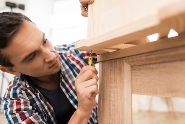 Der Mensch dreht Bolzen in Holzschrank