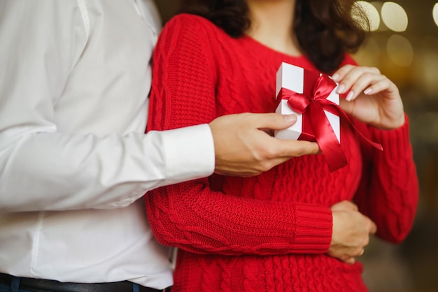 Der Mensch gibt seiner Frau eine Geschenkbox mit rotem Band Ein liebevolles Paar, das den Valentinstag feiert