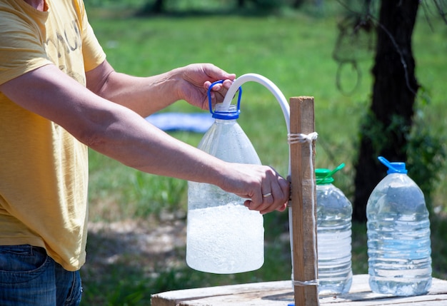 Der Mensch gießt Wasser in eine Flasche auf die Natur