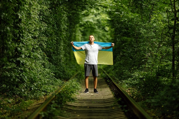 Der Mensch hob die Hände und hält die ukrainische Flagge hinter seinem Rückenkonzept Ukrainische Patriotenkundgebung zur Unterstützung der Ukraine