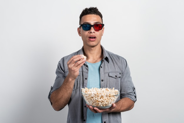 Der Mensch in der 3D-Brille steht mit einem Teller Popcorn in den Händen