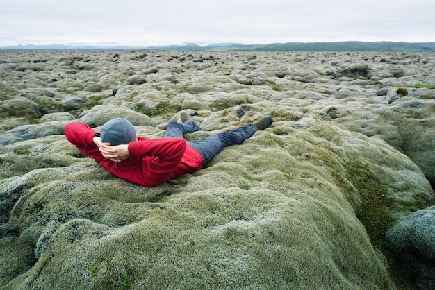Der Mensch ist ein Reisender auf Moos auf einem Lavafeld in Island