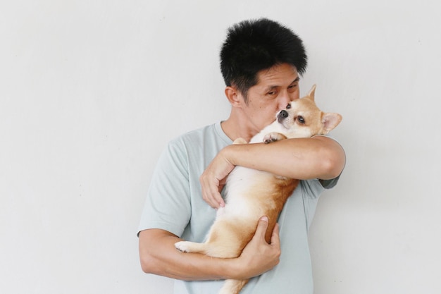 Der Mensch liebt und küsst den süßen Hund des Hundes, der von einem guten Haustier im Haus umarmt wird