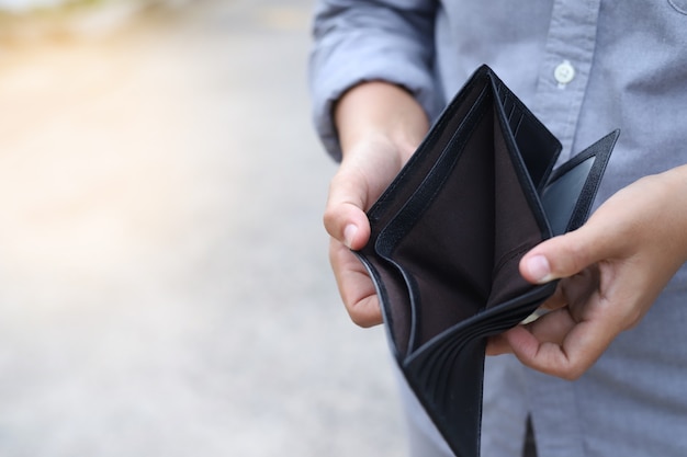 Der Mensch öffnet eine leere Brieftasche wegen der Auswirkungen des Wirtschaftsabschwungs.