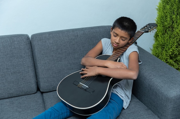Der mexikanische Junge schläft während des Gitarrenunterrichts zu Hause, weil das Coronavirus gesperrt ist