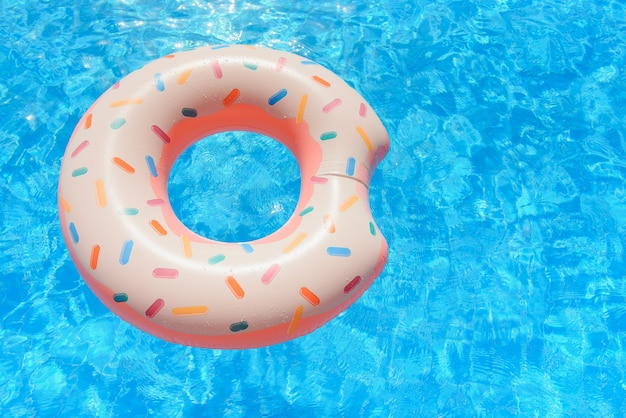 Der mit Hipster besprühte Donut schwimmt im sonnigen Poolhintergrund direkt auf hellem klarem Poolwasser