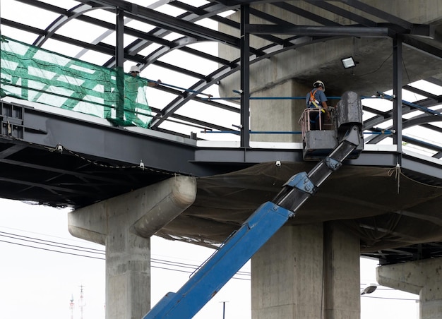 Der Monteur in der Schaufel des Kranwagens zur Überprüfung des Metallrahmens