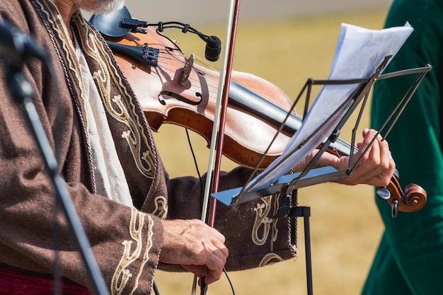 Der Musiker in einem alten Kostüm spielt Geige auf den Noten_