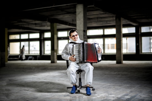 Der Musiker spielt Mundharmonika, Ziehharmonika in der Säulenhalle, Fabrikgelände