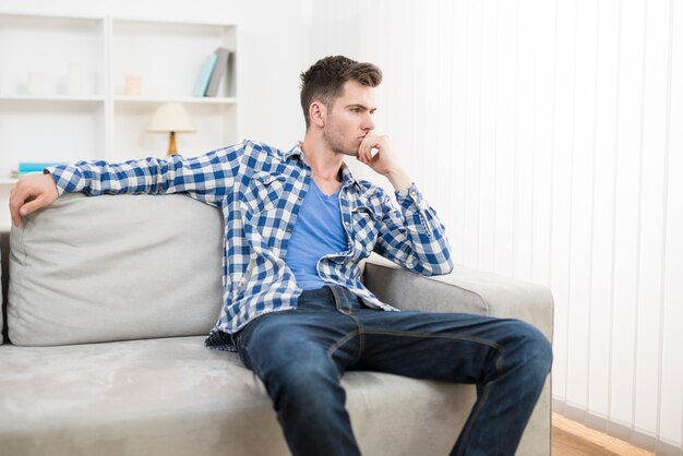 Der nachdenkliche Mann sitzt auf dem Sofa