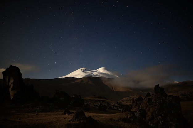 Foto der nächtliche sternenhimmel über dem elbrus. der berg wird vom licht des vollmondes beleuchtet. nordkaukasus.