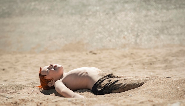Der neunjährige Junge am Strand gräbt sich in den Sand