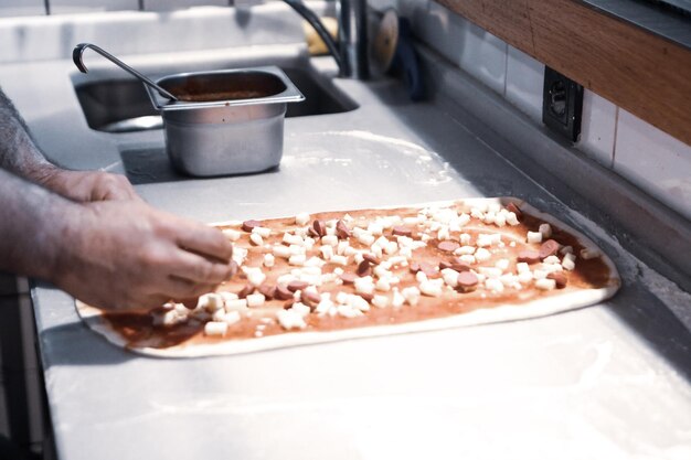 Der Pizzabäcker hat in einer gewerblichen Küche Sauce auf den Boden gelegt
