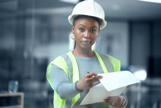 Der Plan ist alles. Abgeschnittenes Porträt einer attraktiven jungen Architektin, die sich Baupläne ansieht, während sie in ihrem Büro steht.