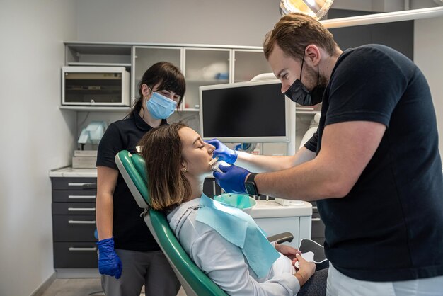 Der Praxiszahnarzt überprüft den Grad der Aufhellung der Zähne des Patienten, indem er sie vom Arzt färbt