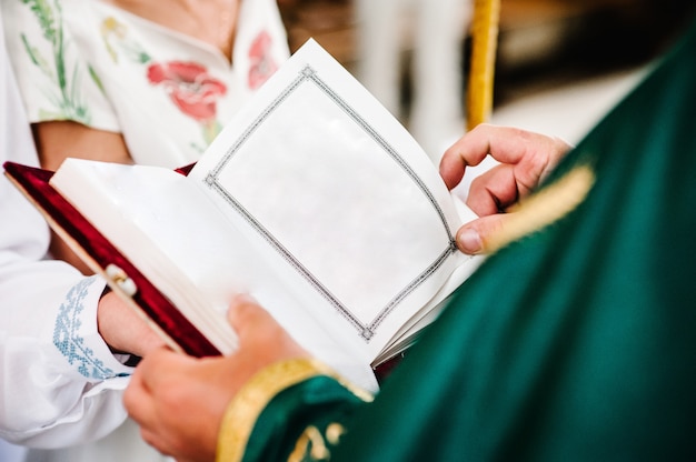 Der Priester hält und liest die Bibel in seinen Händen