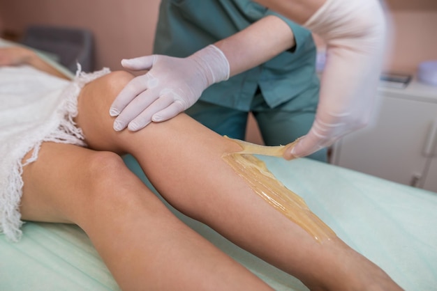 Der prozess der epilation der beine oder körperteile der frau mit der sugaring-methode entfernung unerwünschter haare körperpflege in einem schönheitssalon