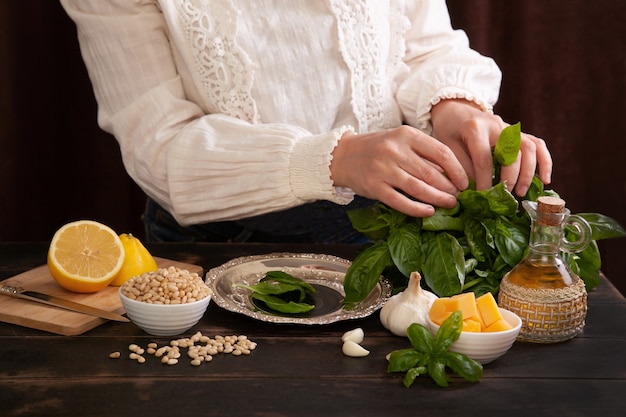 Der Prozess der Herstellung von Pesto-Sauce zu Hause. Eine Frau zupft Blätter von einem Basilikumzweig