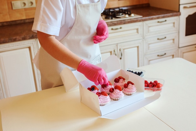 Der Prozess des Kochens köstlicher Cupcakes mit geschlagener Fruchtcreme, dekoriert mit Himbeeren