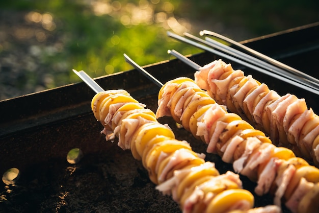 Der Prozess des Kochens von Schaschlik aus Schweinefleisch und Kartoffeln mit Schmalzstücken am Spieß