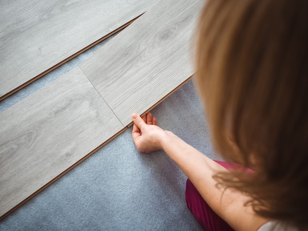 Foto der reparaturvorgang in der wohnung. das mädchen legt das laminat auf den boden. rückansicht