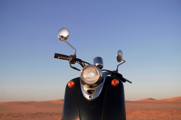 Foto der retro-schwarze roller beim sonnenuntergang im goldenen sand der namib-wüste