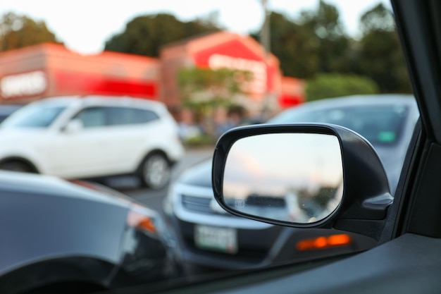 Der Rückspiegel des Autos spiegelt eine malerische Straße dahinter wider. Der Spiegel symbolisiert Nostalgiereflexion